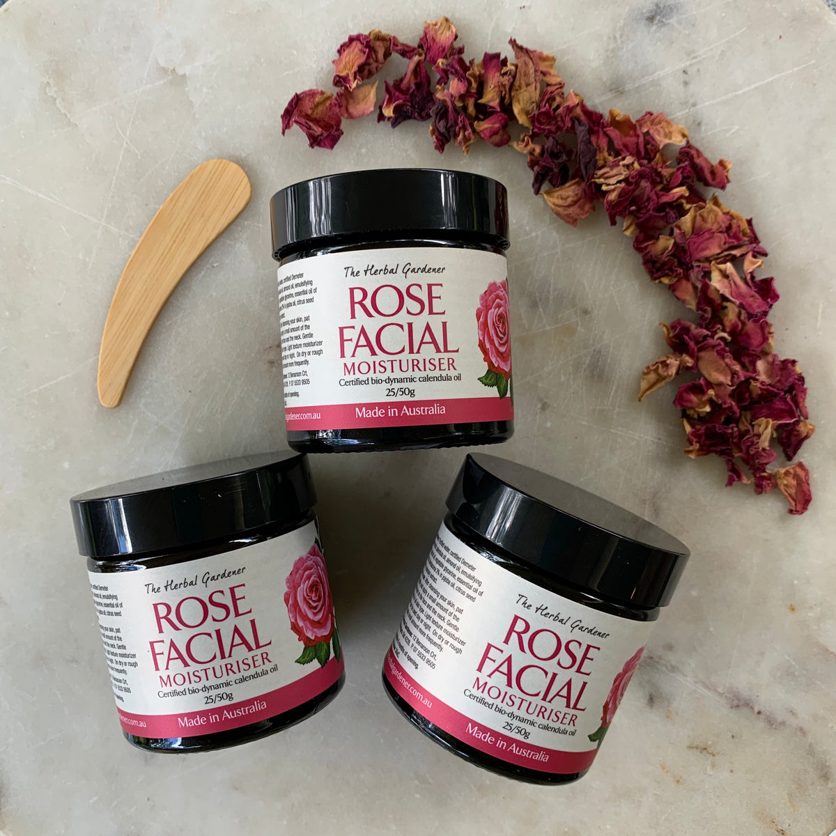 Rose Facial Moisturiser Three Pack 50gr each with a wooden spoon and dried rose petals on a marble surface The Herbal Gardener