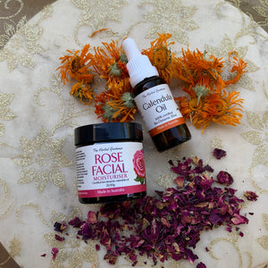 Glowing Rose and Calendula Pack including the rose facial moisturiser 25gr and calendula oil 20mL on a sparkly fabric with dried rose and calendula The Herbal Gardener