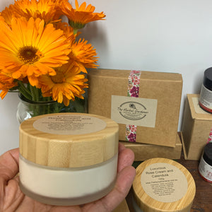 Luxurious Rose and Calendula Cream 100gr in a hand surrounded by fresh calendula flowers The Herbal Gardener